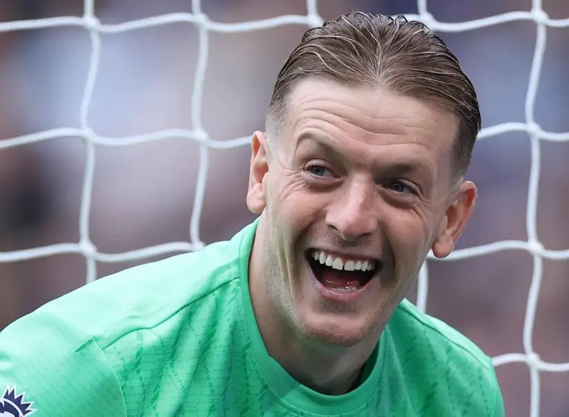 喬丹·皮克福德(Jordan Pickford)身穿綠色守門員球衣,在球門前露出笑容的畫面。