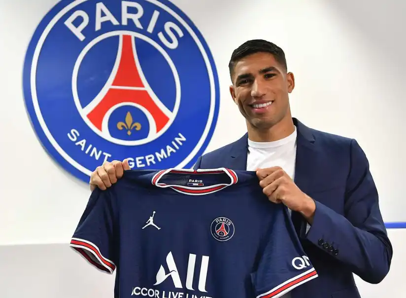 摩洛哥足球員阿什拉夫·哈基米(Achraf Hakimi)手持巴黎聖日耳曼球衣於球隊標誌前合影