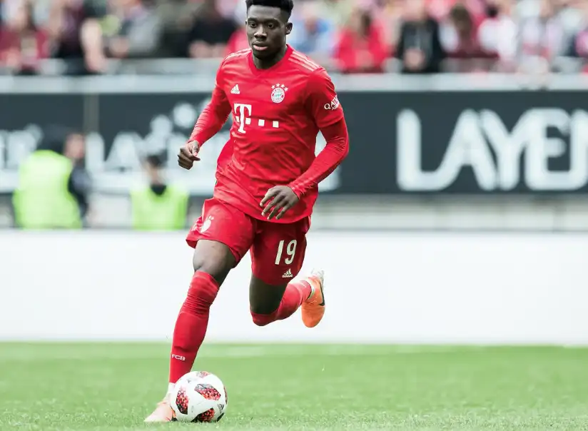 加拿大足球員阿方索·戴維斯(Alphonso Davies)身穿拜仁慕尼黑紅色球衣,在球場上帶球推進的比賽畫面